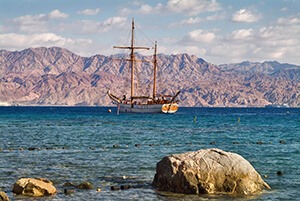 Enormous picturesque stones and a sailing yacht in coastal waters of a resort Eilat in Israel